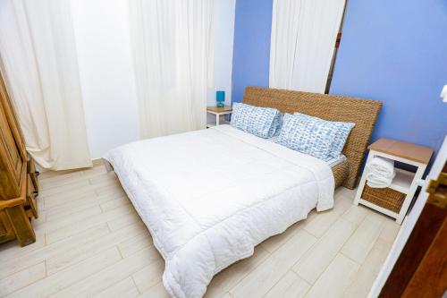 a bedroom with a white bed and blue walls at CoastalCharms Zanzibar in Zanzibar City