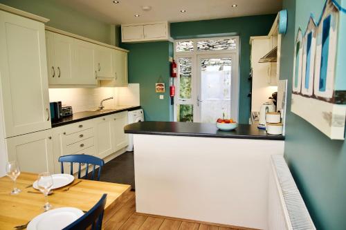 a kitchen with green walls and a table with chairs at Tegfryn (Sleeps 8), 5*, Sea View, Borth y Gest in Porthmadog