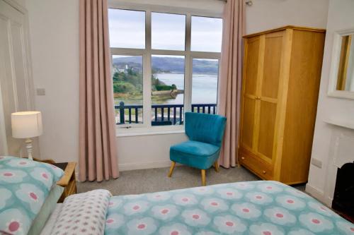 a bedroom with a bed and a blue chair and a window at Tegfryn (Sleeps 8), 5*, Sea View, Borth y Gest in Porthmadog