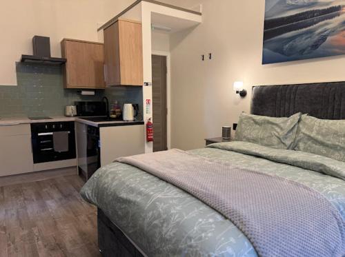 a bedroom with a large bed and a kitchen at Brand new modern, quirky and stylish studio apartment in Sheffield