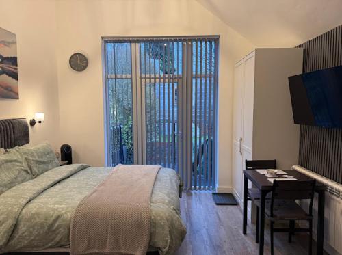 a bedroom with a bed and a desk and a window at Brand new modern, quirky and stylish studio apartment in Sheffield