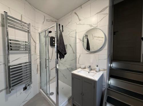 a bathroom with a shower and a sink and a mirror at Brand new modern, quirky and stylish studio apartment in Sheffield