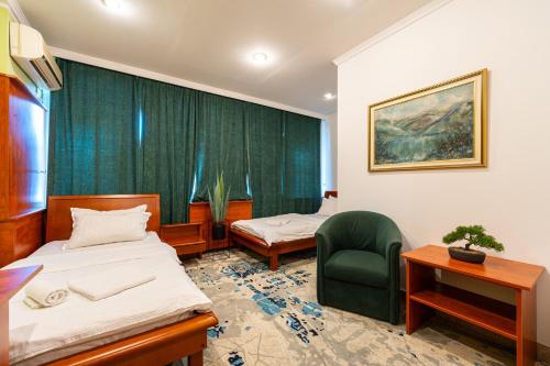 a room with two beds and a green chair at Hotel Bojatours in Podgorica