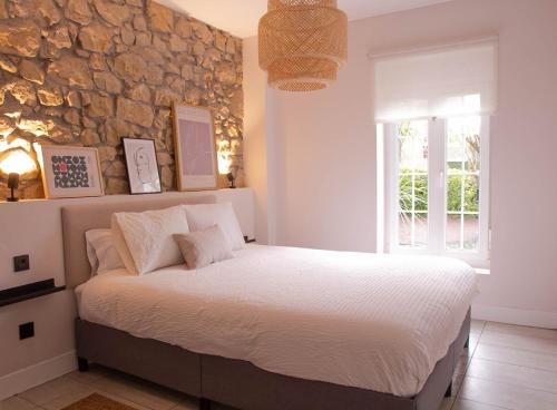 a bedroom with a bed with a stone wall at Arbide House in Leioa