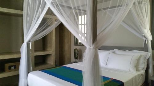 a bedroom with a canopy bed with white curtains at Thalpe Bungalows in Unawatuna