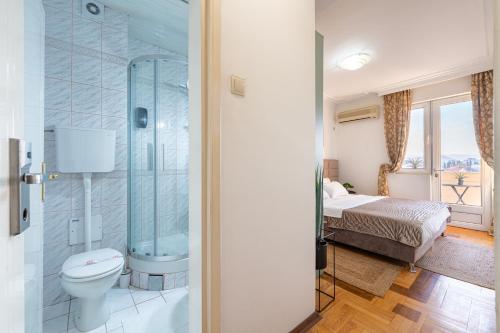 a bathroom with a toilet and a shower and a bed at Hotel Bojatours in Podgorica