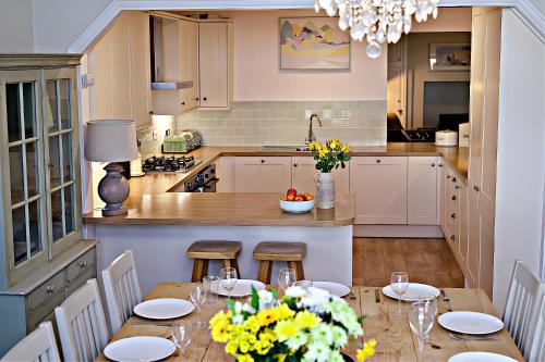 a kitchen with a table with chairs and a dining room at Bay View, Sleeps 18, 7 Bedrooms, 7 Bathrooms, Seafront, Criccieth in Criccieth