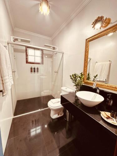 a bathroom with a sink and a toilet and a mirror at Cadivó Chalé Lavras Novas in Ouro Preto