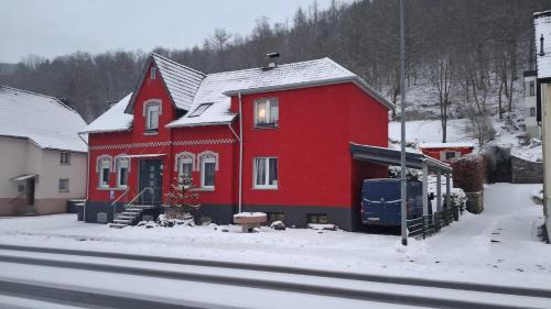 a red house with snow on the ground next to a street at Wunderschönes Sauerland in Plettenberg