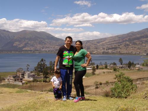 a man and a woman and a child standing on a hill at Hostal y Complejo Recreacional La Playita de Monse in Otavalo