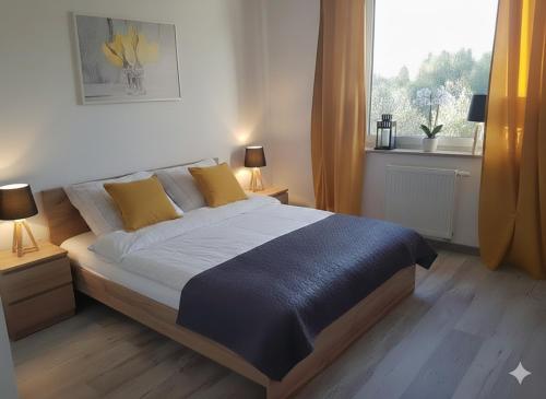 a bedroom with a bed with yellow pillows and a window at Caskada Modern Apartments 2 NOWY APARTAMENTOWIEC WINDA in Słupsk
