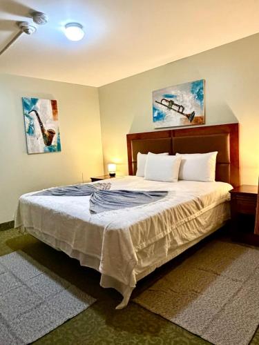 a bedroom with a large bed with two paintings on the wall at Rocky Mountain Lodge & Suites in Renfrew