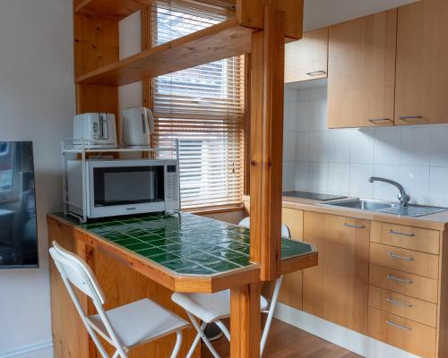 a kitchen with a counter with a microwave and a sink at Studio apartment next to Highgate tube station in London