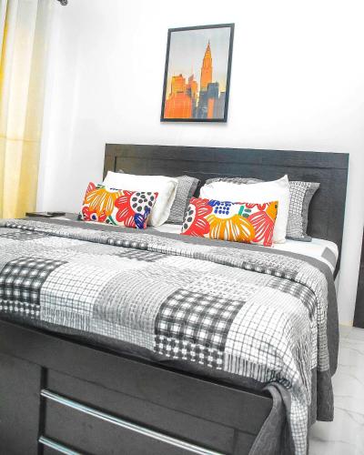 a bed with a black and white comforter and pillows at 3Tee Serviced Apartment Abeokuta in Abeokuta