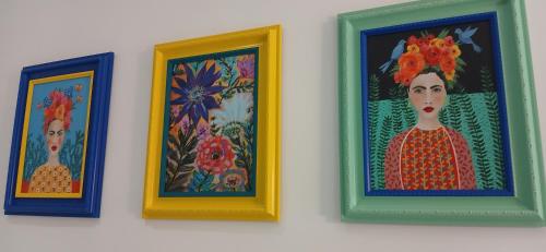 three paintings of women are hanging on a wall at Seaside Apartment in Moreton