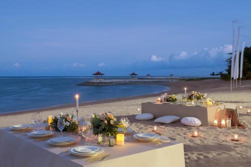 a table on the beach with candles and flowers at Griya Santrian a Beach Resort And Spa in Sanur