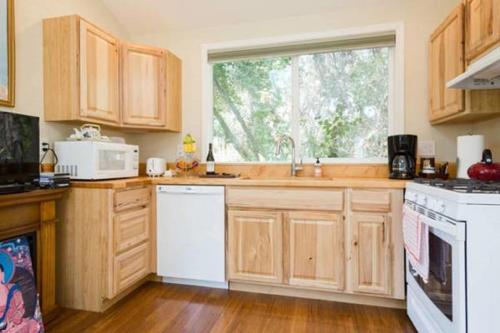 una cocina con armarios de madera y una gran ventana en Amitabha Wine Country Cottage, en Santa Rosa