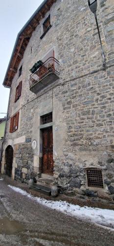 un edificio in pietra con un balcone e una porta di legno di Ginny a Bormio