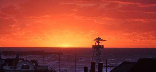 a sunset with a lighthouse on top of a building at Luxury 1 Bed Apt Central Brighton Private Garden Sleeps 6 in Brighton & Hove