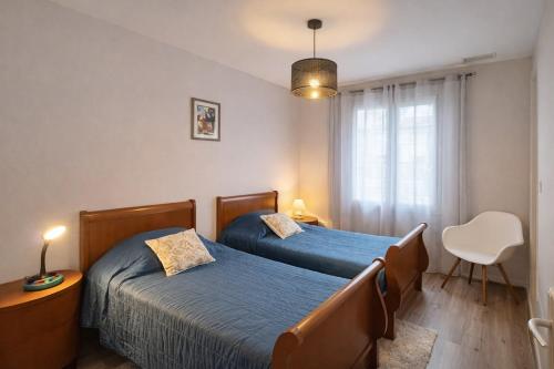 a bedroom with two beds and a chair and a window at Gite Lagarrigue in Lavaur