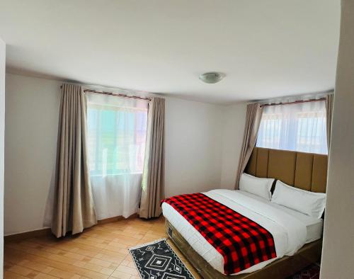 a bedroom with a bed with a plaid blanket on it at Mara Balanite Hotel in Masai Mara