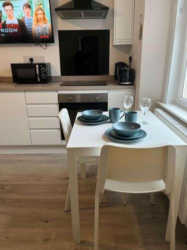 a kitchen with a white table with plates and wine glasses at 1 Bed Room Flat Close to seafront in Weston-super-Mare