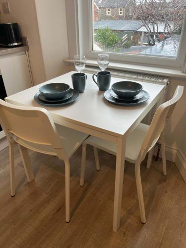 a white table with chairs and plates and glasses on it at 1 Bed Room Flat Close to seafront in Weston-super-Mare