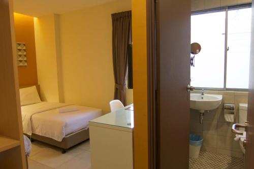 a small room with a bed and a sink at Hotel 1000 Miles in Kuala Lumpur