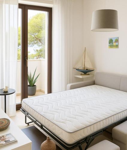 a white bedroom with a bed in a room at Casabaja in Baja Sardinia