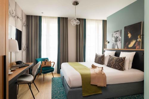 a hotel room with a large bed and a desk at Lyric Hotel Paris Opera in Paris