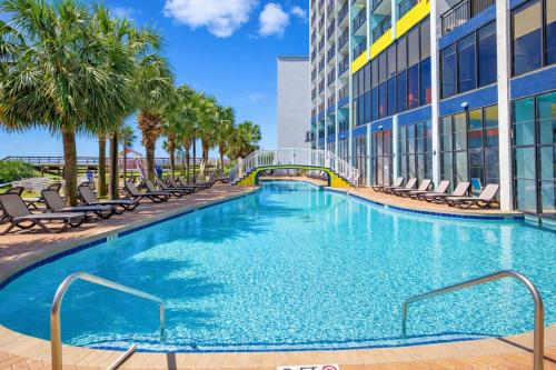 a swimming pool in a building with chairs and palm trees at Heated Pools, Heated lazy river, 3 hot tubs-Privately owned Oceanfront renovated condo on 12th floor in Myrtle Beach