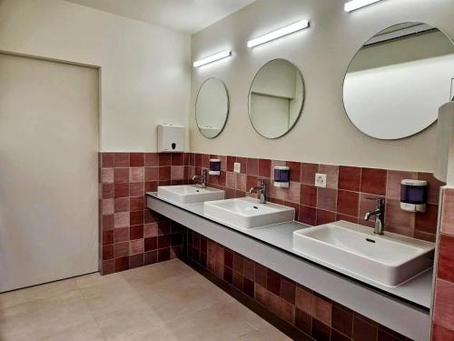 a bathroom with three sinks and two mirrors at Green Marmot Capsule Hotel Genève - Self check-in in Geneva