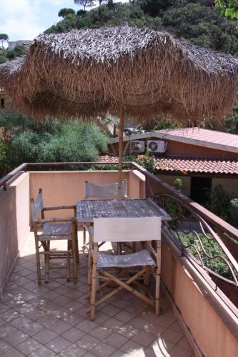 a table and two chairs and an umbrella on a balcony at Solemare Club Village in Capo Vaticano