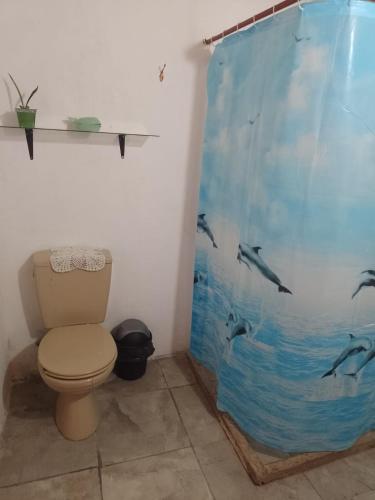a bathroom with a toilet with dolphins shower curtain at Casona Estación Cabra Corral in Coronel Moldes