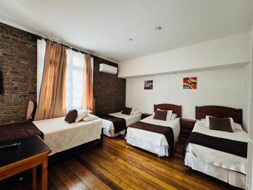 a hotel room with three beds and a piano at Hotel Casa Lyon in Santiago