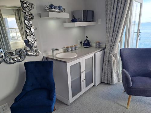 a bathroom with a sink and a mirror and a chair at Boutique Inn - Azure in Gordonʼs Bay