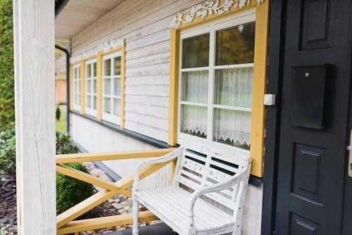 a white bench sitting on the front porch of a house at Villa Kurorto Namas in Druskininkai