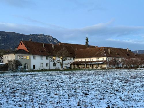 a building with snow on the ground next to a field at Klosterherberge Solothurn Self Check-in in Solothurn