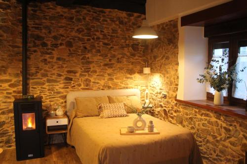a bedroom with a bed and a stone wall at MINI PICONEIRO II in Pravia