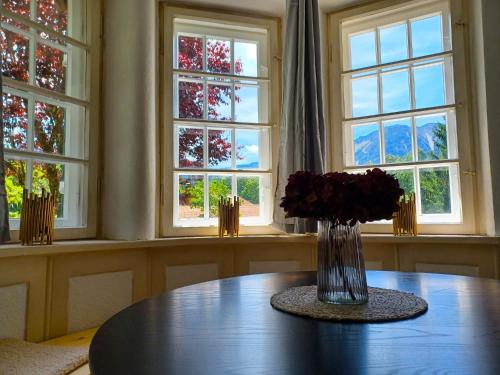 a vase of flowers on a table in front of windows at Ferienwohnung 'Bergidylle' - Zu Fuß auf die Loipe und den Berg, nur wenige Minuten ins Skigebiet in Bayrischzell