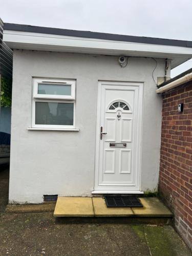 a white door on a white house with a window at Modern Studio flat with free parking in Langley Marish