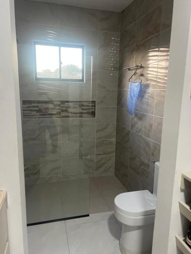 a bathroom with a shower with a toilet and a window at Villa Sabanilla Casa bifamiliar campestre con piscina privada Aire acondicionado Tranquilidad total in Puerto Colombia