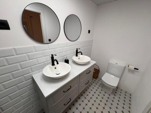 a bathroom with two sinks and a mirror and a toilet at Finca Alboroto in Huesca