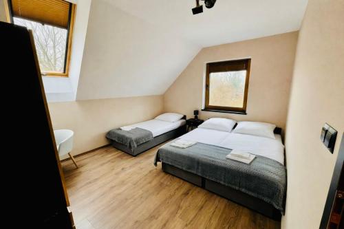 a bedroom with two beds and two windows at Na Fali Marszałka in Mielenko