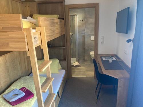 a small room with a bunk bed and a desk at Pension Haus Georg in Westendorf