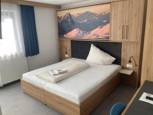a bedroom with a bed with a picture on the wall at Pension Haus Georg in Westendorf