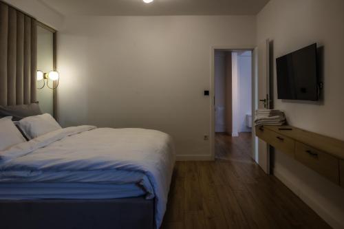a bedroom with a bed and a flat screen tv at Mirror Apartments in Satu Mare