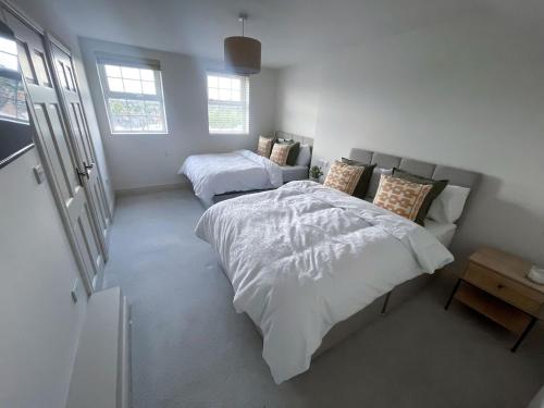 a bedroom with two beds and a table and two windows at The Haven in Banbridge
