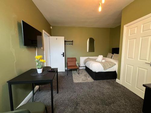 a bedroom with a bed and a table and a door at Hayy Studio Quiet Comfy Connected in Huddersfield