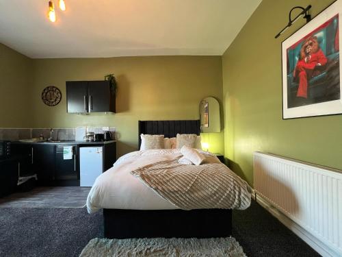 a bedroom with a bed and a kitchen at Hayy Studio Quiet Comfy Connected in Huddersfield